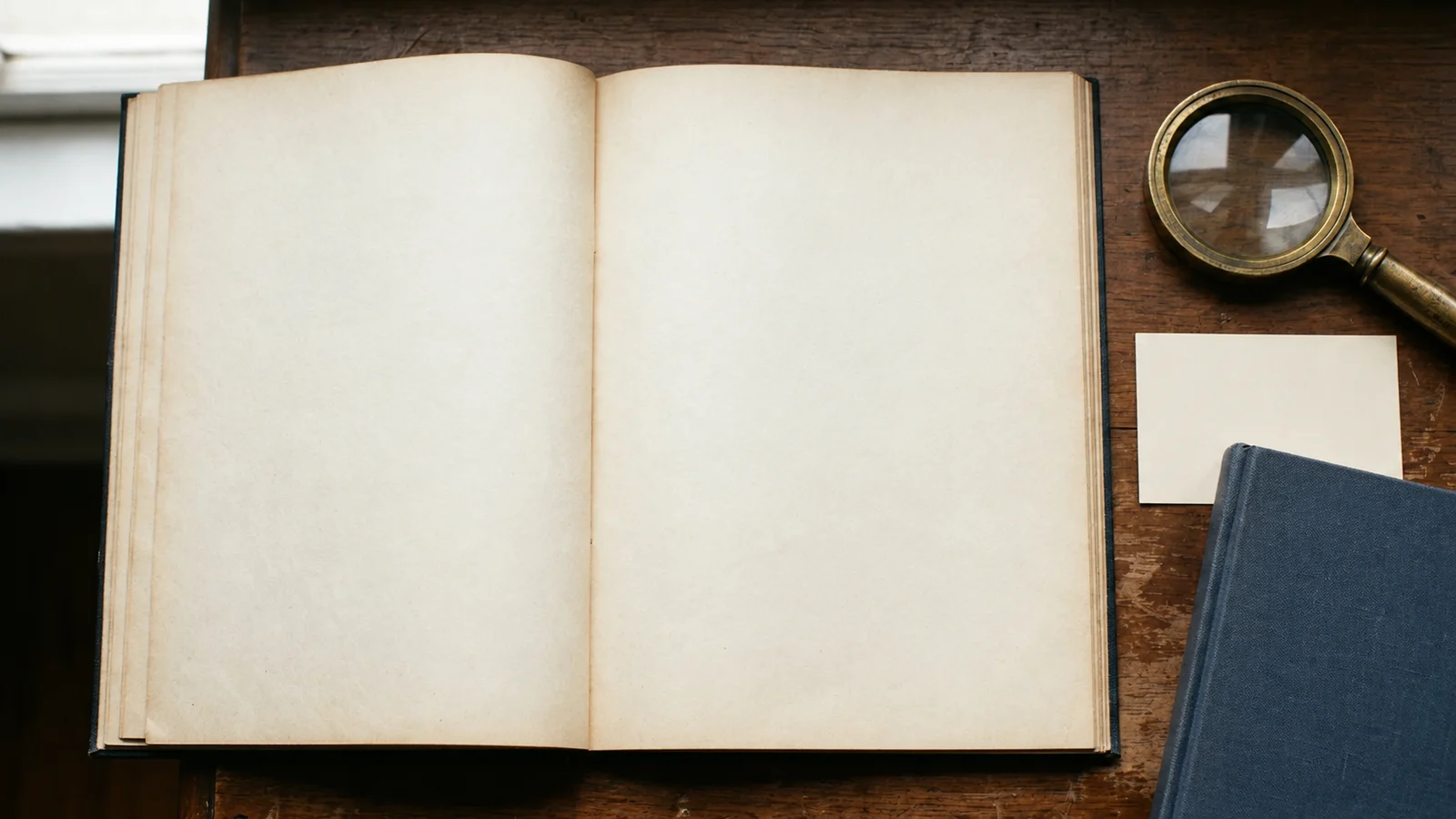 Open blank protocol notebook beside a brass magnifying glass, a blank card and a navy notebook on a wooden research desk in soft daylight.
